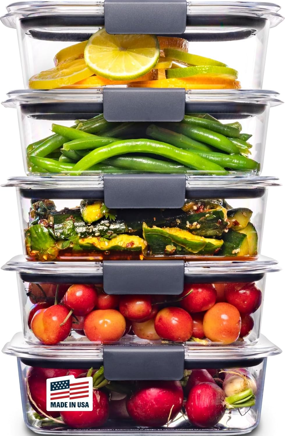 A stack of five clear glass food storage containers with dark gray lids, filled with fresh vegetables and fruit including lemons, green beans, zucchini, tomatoes, and radishes, on a white background.