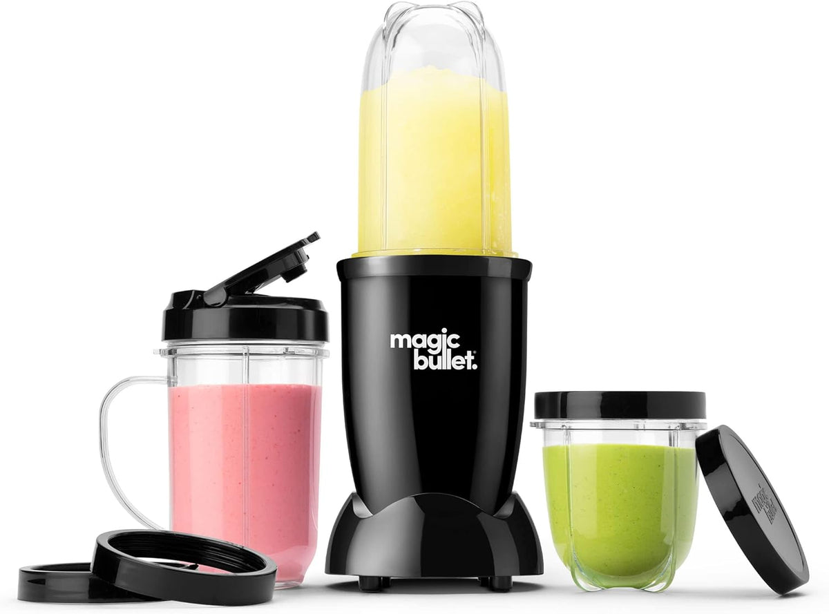 Black magic bullet personal blender with three clear cups holding yellow, pink and green drinks, plus lids and cup rings.
