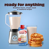 Blender with a glass of milk, protein powder, and waffles on a blue background