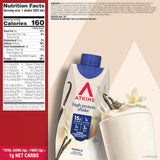 A bag of Atkins high protein shake vanilla flavor shown with a Nutrition Facts panel on the left and vanilla beans and a scoop of powder, all on a beige background.